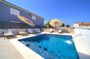 basen z leżakami i parasolami obok domu w obiekcie Villa QUARNARO with heated pool w mieście Omišalj