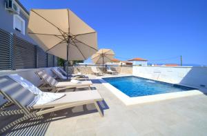 a swimming pool with lounge chairs and an umbrella at Villa QUARNARO with heated pool in Omišalj