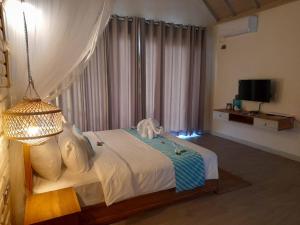 a bedroom with a bed with a lamp and a television at Oruwa Boutique Villas in Arugam Bay