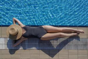 a woman in a hat laying on the side of a swimming pool at Agionissi Resort in Ammouliani