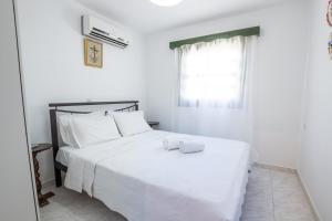 a white bedroom with a large white bed with a window at Mertonas Villa in Karpathos