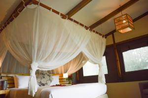 een slaapkamer met een hemelbed en witte gordijnen bij Adrift River Club in Kangulumira