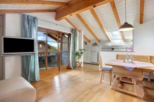 a living room with a dining table and a tv at Josys Ferienwohnung in Gstadt am Chiemsee