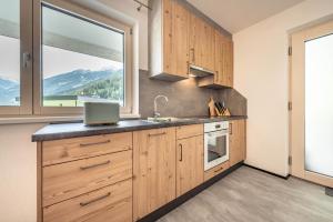 eine Küche mit Holzschränken und einem großen Fenster in der Unterkunft Bliem, Apartment in Finkenberg