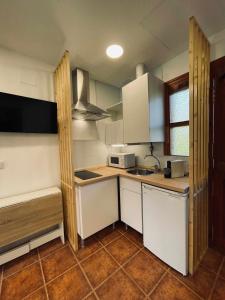 małą kuchnię z białymi szafkami i zlewem w obiekcie Apartamento familiar cercano a playa de Rodiles 5 w mieście Villaviciosa