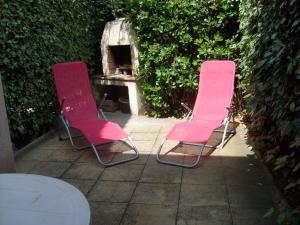 2 chaises roses assises sur une terrasse à côté d'une table dans l'établissement JOLI T2 RDC, BORD DE MER , PISCINE , Aresquiers FRONTIGNAN PLAGE 34, à Frontignan