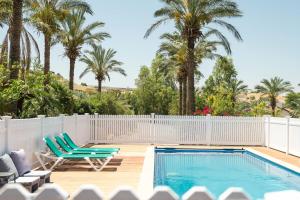 a pool with two chairs and a fence and palm trees at Naomi's place הבית של נעמי in Moshav Ramot