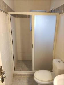 a bathroom with a toilet and a glass shower door at ROMVI VILLAGE in Amaliás