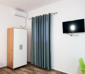 Zimmer mit einem TV und einem Vorhang. in der Unterkunft Gray&Oli Studios in Vlorë