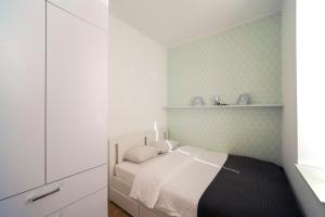 Habitación blanca pequeña con cama y estanterías en Green Leaf Apartment en Zagreb