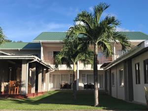 two palm trees in front of a building at Panorama Guesthouse Apartments Beau Vallon Beach in Beau Vallon