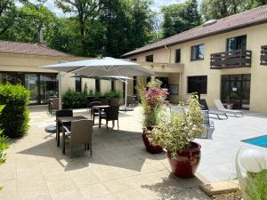 eine Terrasse mit Tischen, Stühlen und einem Sonnenschirm in der Unterkunft Enzo Hôtels - ST Eloy Metz Amneville By Kyriad Direct in Amnéville