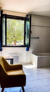 La salle de bains est pourvue d'une baignoire, d'une chaise et d'une fenêtre. dans l'établissement LOGIS HOTEL & RESTAURANT L'ETAPE Bouc Bel Air - Gardanne, à Bouc-Bel-Air