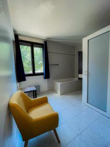 La salle de bains est pourvue d'une chaise jaune et d'une baignoire. dans l'établissement LOGIS HOTEL & RESTAURANT L'ETAPE Bouc Bel Air - Gardanne, à Bouc-Bel-Air