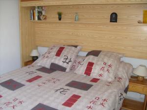 una camera da letto con letto, testiera e cuscini in legno di JOLI T2 RDC, BORD DE MER , PISCINE , Aresquiers FRONTIGNAN PLAGE 34 a Frontignan