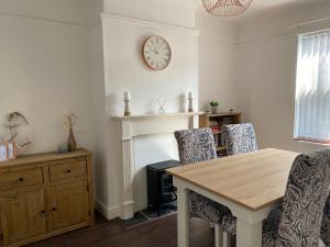 a dining room with a table and chairs and a clock at Ivy Coastal Cottage in Caister-on-Sea