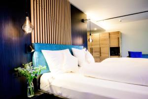 ein Schlafzimmer mit einem weißen Bett und einer Vase aus Blumen in der Unterkunft Aqua Blu Hotel in Bad Füssing