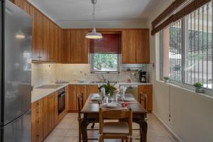a kitchen with wooden cabinets and a table with chairs at Casa Regina - 5min to Beach - Peaceful Retreat in Lithakia
