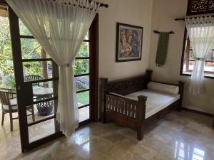 1 dormitorio con 1 cama y ventanas con cortinas en Rumah Kelapa Villa Alami, en Karangasem