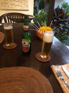 dois copos de cerveja sentados numa mesa de madeira em Rumah Kelapa Villa Alami em Karangasem