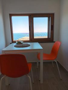 un tavolo e due sedie in una stanza con due finestre di Pietra Fiorita Cottage a Pisciotta