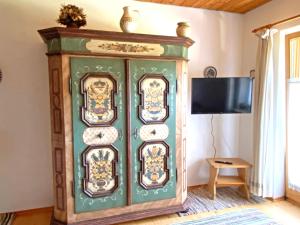 a green cabinet in a room with a tv at Ferienwohnung Sonnenschein in Sachrang