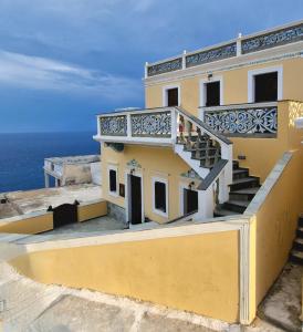 un edificio giallo con scale e l'oceano sullo sfondo di Kyano seaview a Olympos