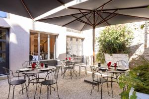 patio con tavoli e sedie sotto ombrellone di Carmel 1643 ad Arbois