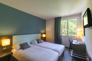 a hotel room with two beds and a window at Hôtel Miramont in Lourdes