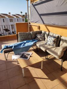 un patio avec des canapés et une table sur le toit dans l'établissement Apartamento con gran terraza a 50 m de la playa, à San Luis de Sabinillas