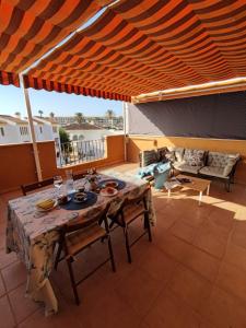 eine Terrasse mit einem Tisch und Stühlen unter einer hölzernen Pergola in der Unterkunft Apartamento con gran terraza a 50 m de la playa in San Luis de Sabinillas