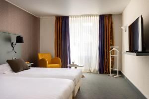 um quarto de hotel com duas camas e uma televisão em Carmel 1643 em Arbois