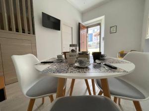 a dining room with a table and white chairs at Il Vicoletto - Tassitani Vacanze in Corigliano Calabro