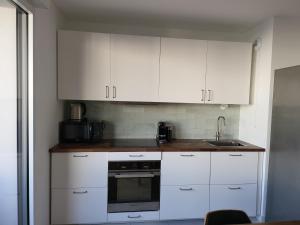 a kitchen with white cabinets and a sink at Superbe Appartement à 3min à pieds de la gare in Chessy