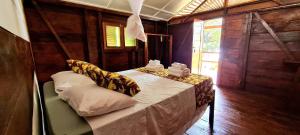 una habitación con una cama y una mesa con almohadas en Gombela Ecolodge and Farming, en São Tomé