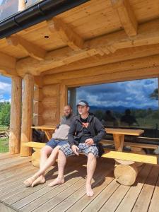deux hommes assis sur un banc dans une cabine dans l'établissement Chata nad Termami VIP, à Dzianisz
