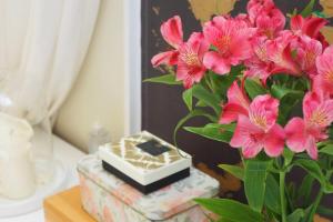 un jarrón con flores rosas y un libro sobre una mesa en Cozy 1 Bedroom Home near the City Centre, en Edimburgo