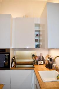 una cocina con armarios blancos y fregadero en Cozy 1 Bedroom Home near the City Centre, en Edimburgo