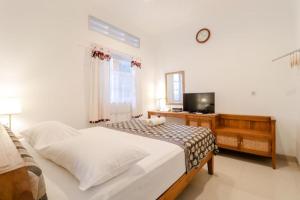 a bedroom with a bed with a television and a desk at Palem Kipas Homestay in Yogyakarta