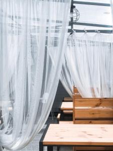 a bedroom with white curtains and a wooden bench at Klaster SeaView Hotel in Chornomorsk