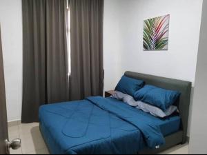 un letto con lenzuola blu in una camera da letto di Pangsapuri Desaru Utama a Bandar Penawar