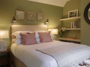 1 dormitorio con 1 cama grande con almohadas rosas en Beehives Cottage at Woodhall Estate, en Hertford