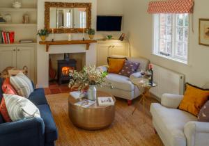 a living room with couches and a fire place at Beehives Cottage at Woodhall Estate in Hertford