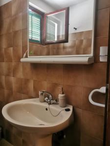 La salle de bains est pourvue d'un lavabo et d'un miroir. dans l'établissement Apartman prvi red do mora Čović, à Duće