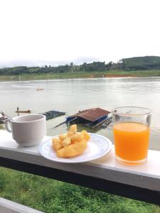 un plato de comida y un vaso de zumo de naranja en Baan Dongsak River view en Sangkhla Buri