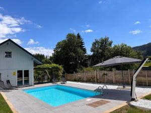 a swimming pool with an umbrella next to a house at Apartment Frank-2 by Interhome in Feldkirchen in Kärnten