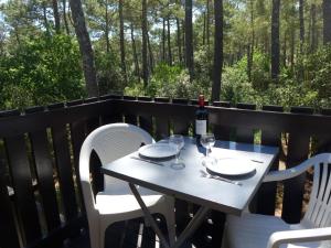 una mesa blanca con 2 sillas y una botella de vino en Apartment Hameau du golf-2 by Interhome, en Lacanau-Océan