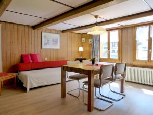 a bedroom with a table and a bed with a red couch at Apartment Grosshorn by Interhome in Lauterbrunnen