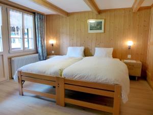 um quarto com uma cama grande e lençóis brancos em Apartment Grosshorn by Interhome em Lauterbrunnen