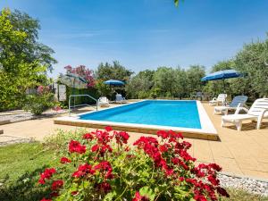 einen Pool mit roten Blumen und blauen Sonnenschirmen in der Unterkunft Holiday Home Sandra by Interhome in Rajki